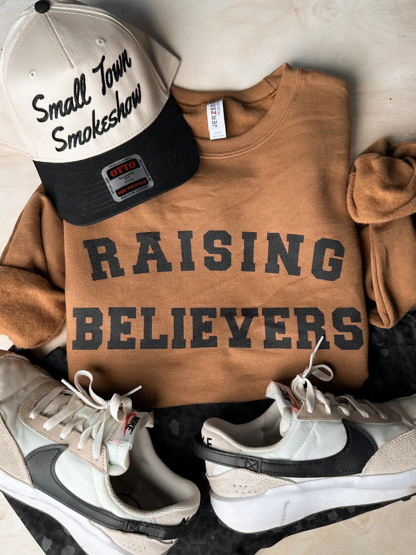 Raising Believers Crewneck — pecan-colored Jerzees sweatshirt with varsity-style faith graphic from Frost Impressions Boutique in Wapakoneta, Ohio.