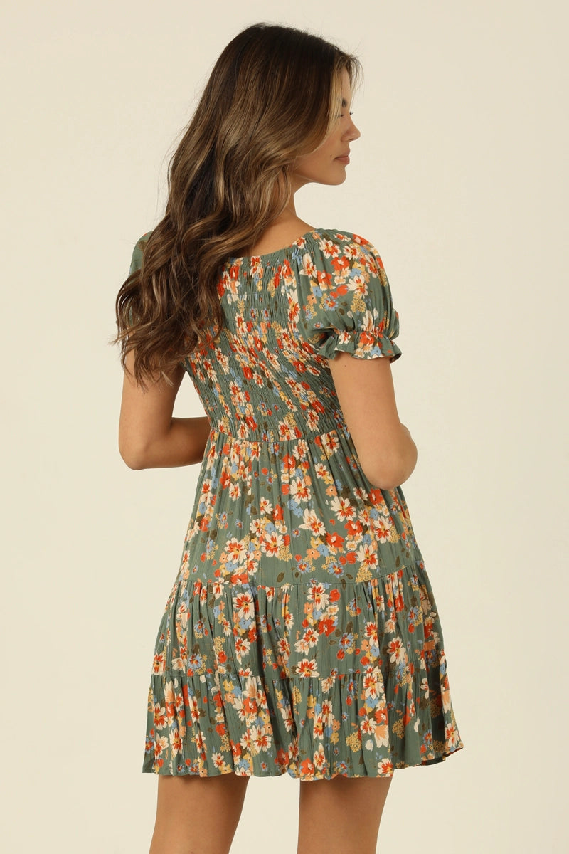 Green floral mini dress with smocked bodice, V-neckline, and short sleeves in a soft sage tone