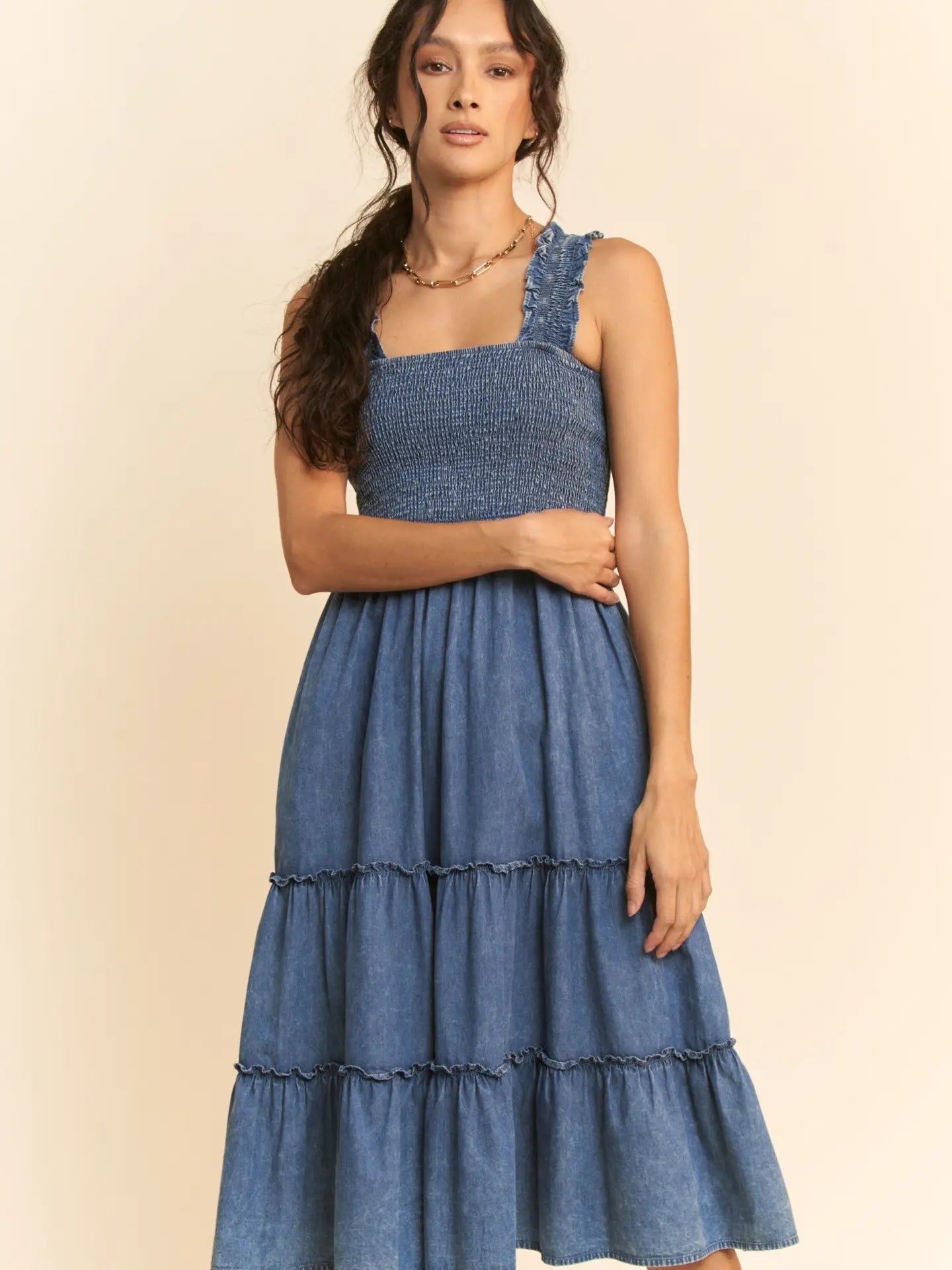 Washed denim midi dress with smocked bodice, adjustable straps, and tiered skirt design