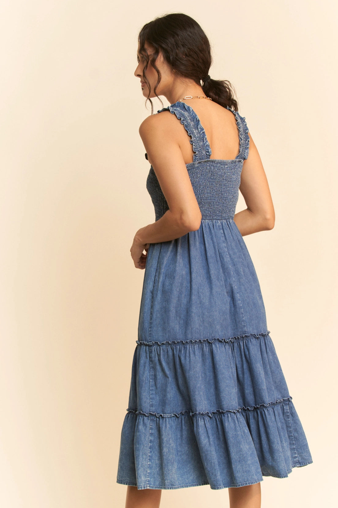 Washed denim midi dress with smocked bodice, adjustable straps, and tiered skirt design
