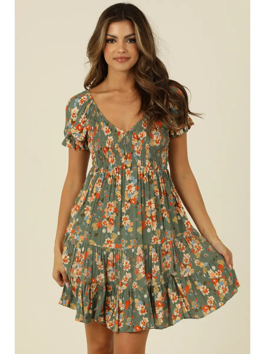 Green floral mini dress with smocked bodice, V-neckline, and short sleeves in a soft sage tone
