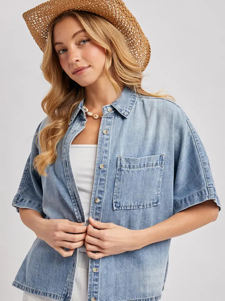 Medium wash short sleeve boxy denim button down shirt with relaxed oversized fit and chest pocket