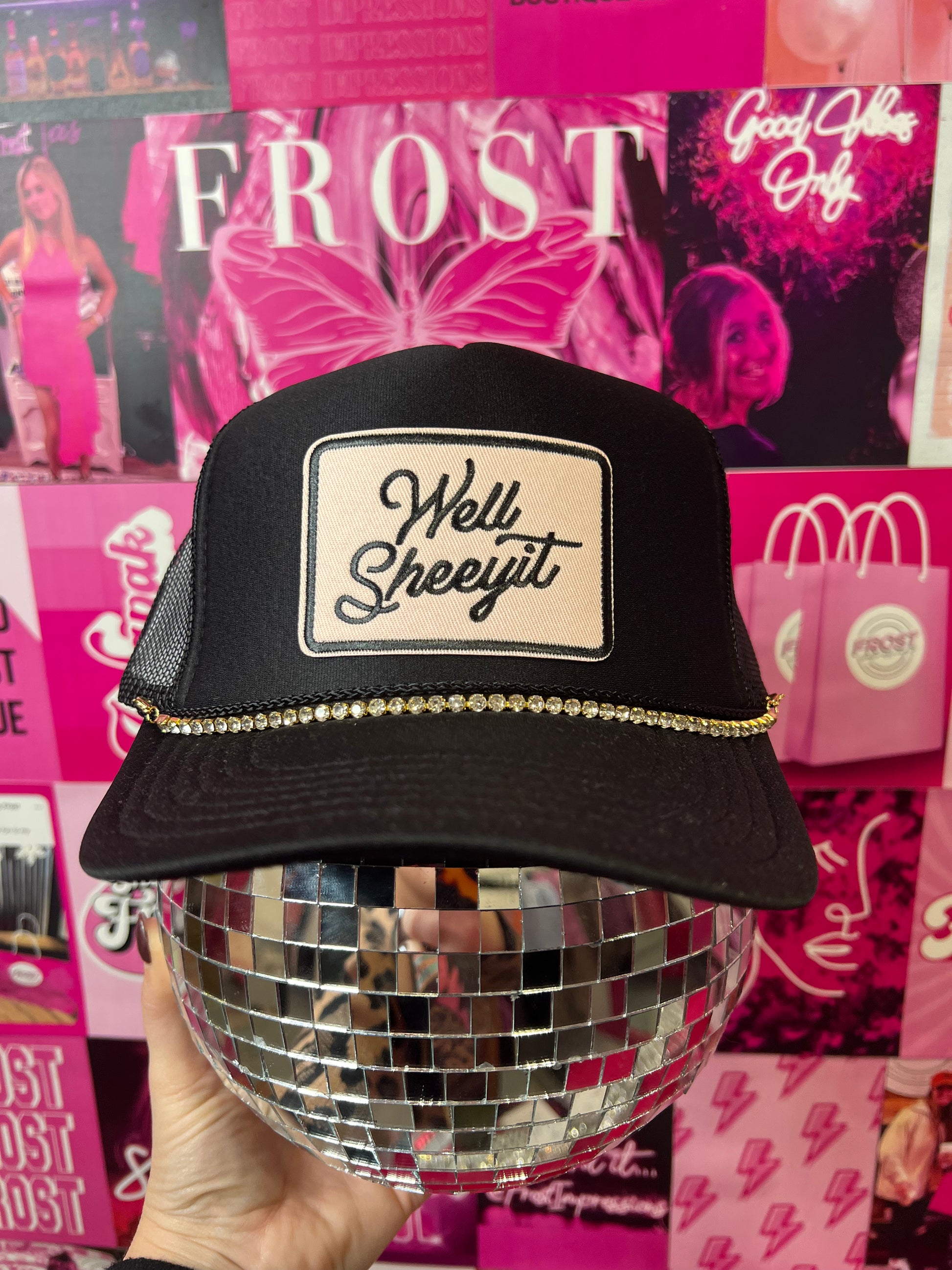 Black trucker hat with “Well Sheeyit” patch and silver hat chain — bold boutique fashion accessory.
