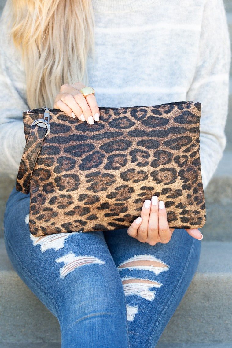 Leopard Luxe Clutch — oversized leopard print vegan leather clutch with wristlet strap and gold grommet detail, available at Frost Impressions Boutique in Wapakoneta, Ohio.