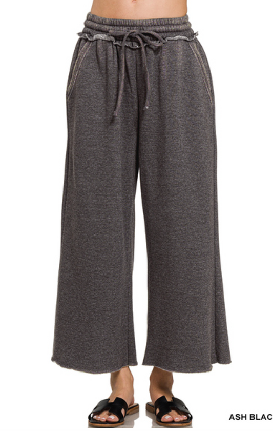 Acid wash fleece palazzo sweatpants with wide leg fit, drawstring waistband, raw hem, and side pockets available in multiple colors