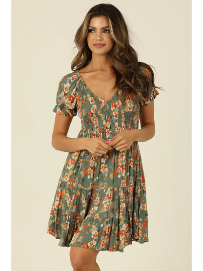 Green floral mini dress with smocked bodice, V-neckline, and short sleeves in a soft sage tone