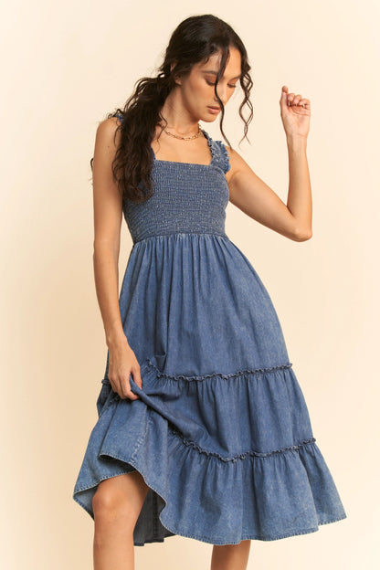 Washed denim midi dress with smocked bodice, adjustable straps, and tiered skirt design