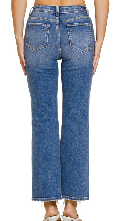Stretch denim jeans with distressed frayed hem, cropped length, and medium wash finish