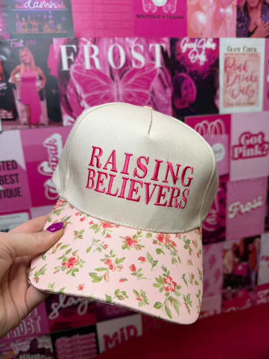 Trucker hat with “Raising Believers” graphic and floral print bill with mesh back