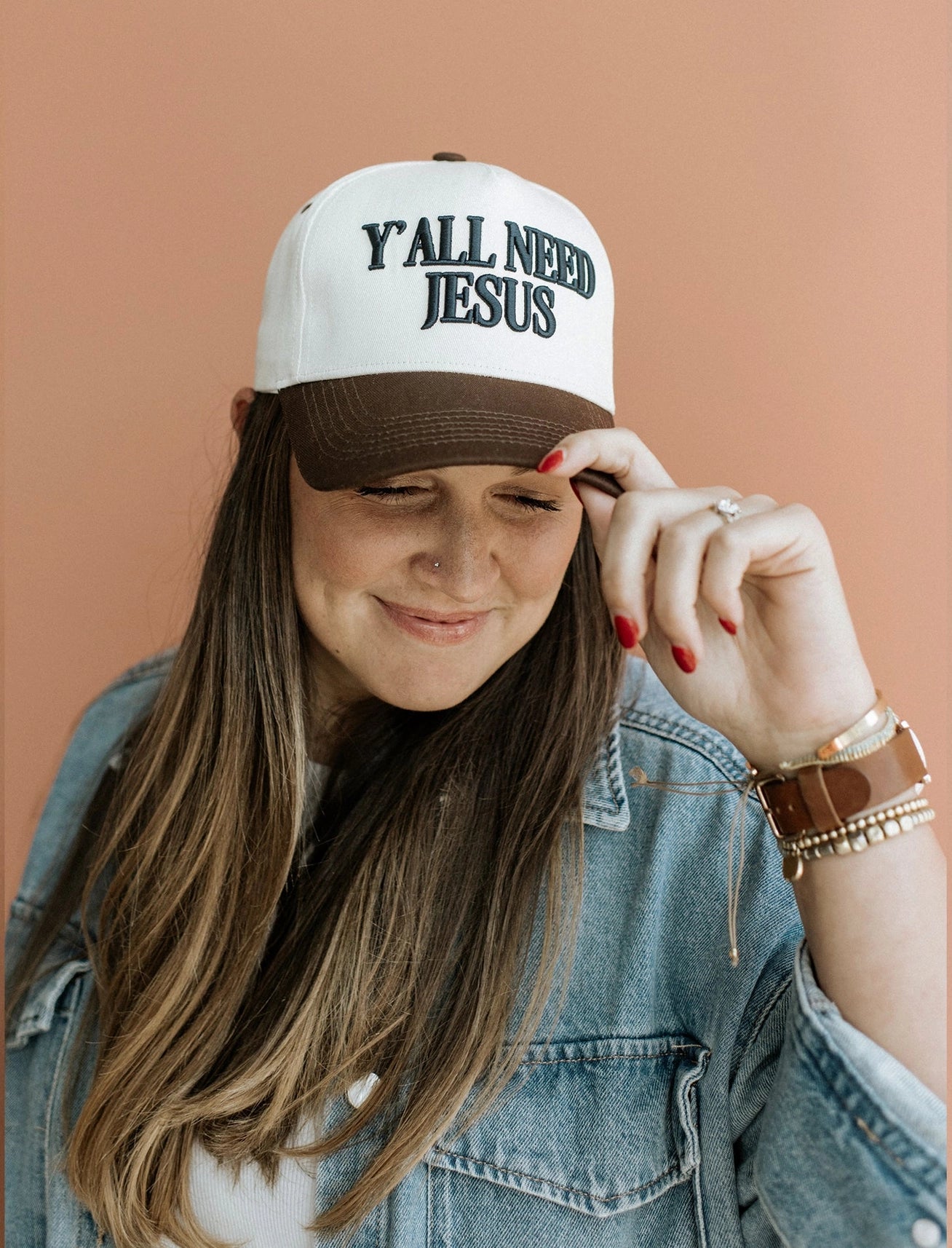 Brown front trucker hat with navy puff embroidery reading “Y’all Need Jesus” — 5-panel snapback style.